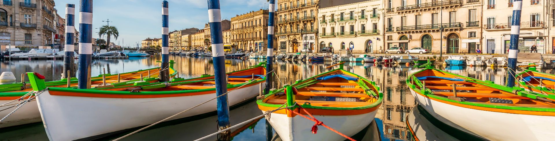 Docked boats sit in a row on still waters in Sete, France.