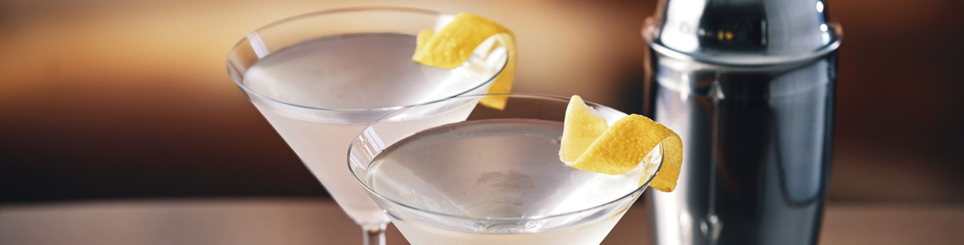 Cold martini's sit freshly prepared garnished with lemon peels.
