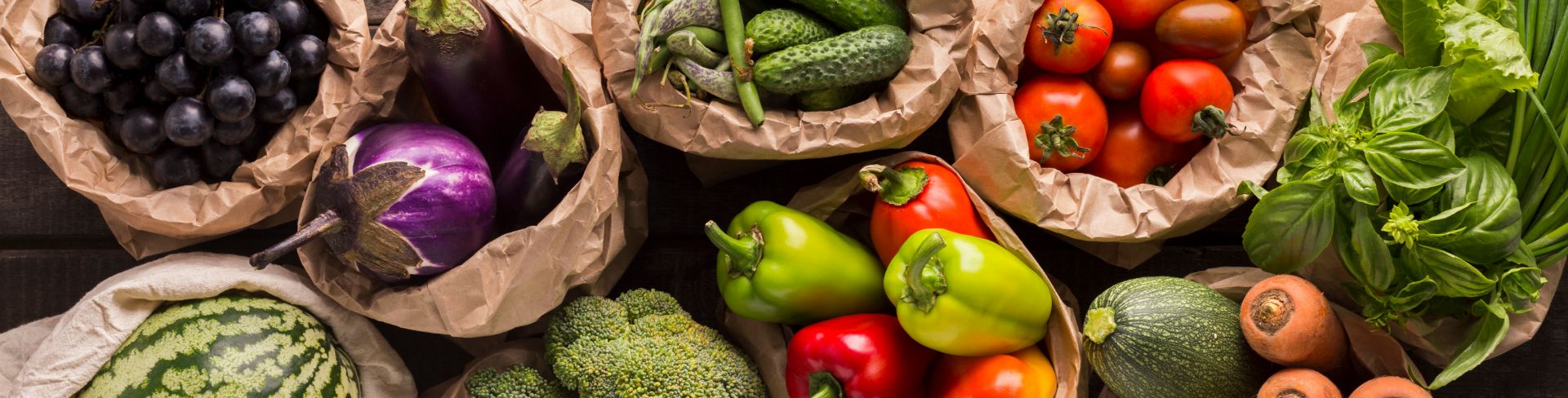 Fresh produce sits in paper bags on a table. 