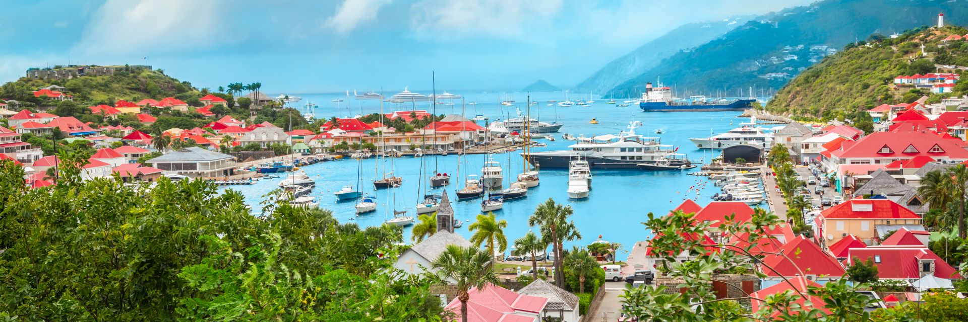 Boats dot a light blue waterway surrounded by lush greenery.
