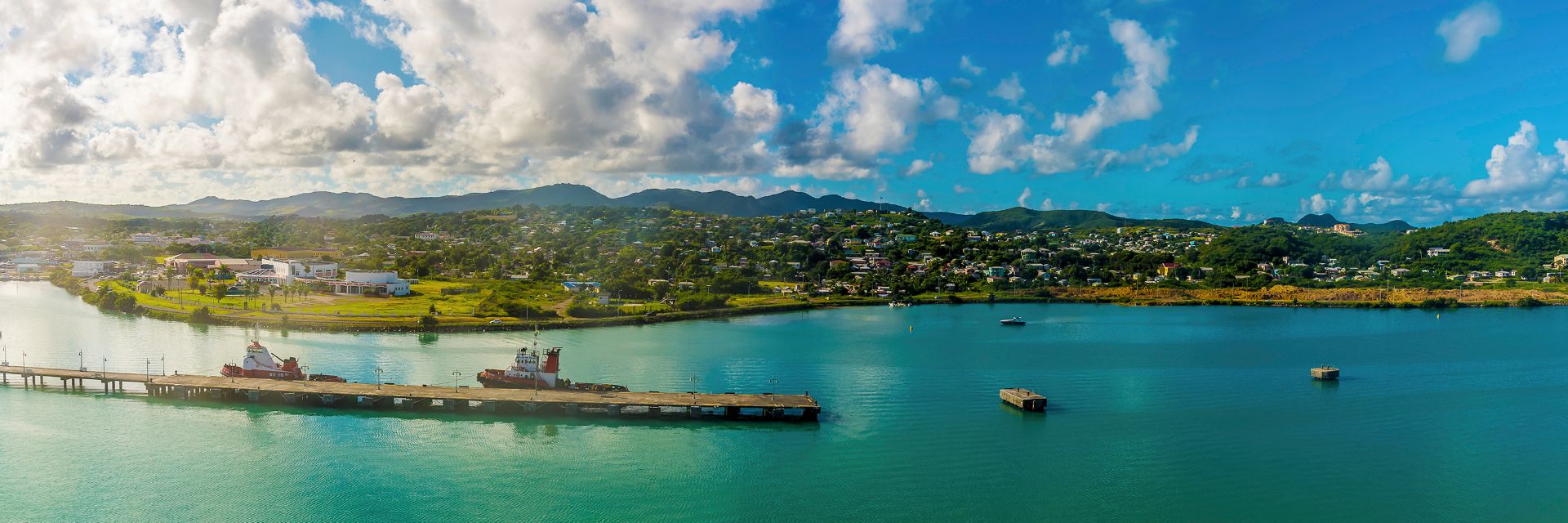 A boat floats through a multicolored waterway with a tree covered island in the background.