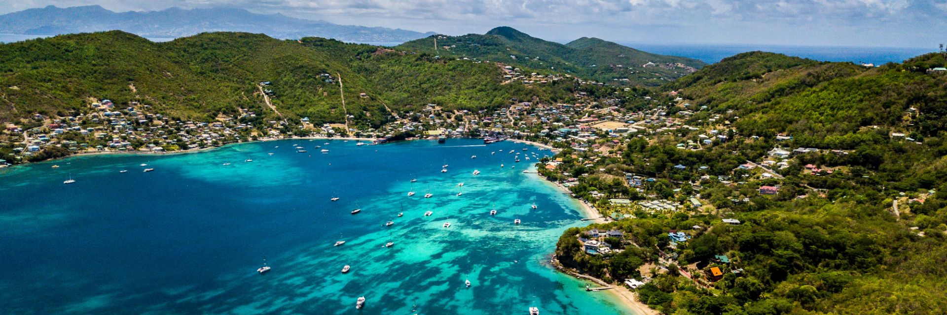 A sandy beach divides a multicolored waterway and a tree covered island.
