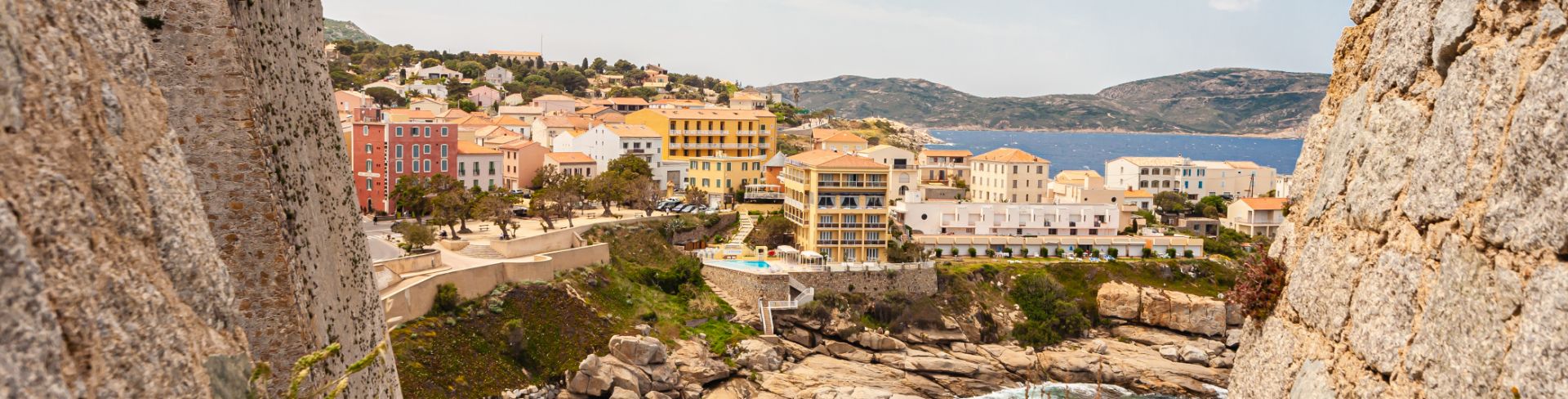 A rocky overlook reveals a city on the water.