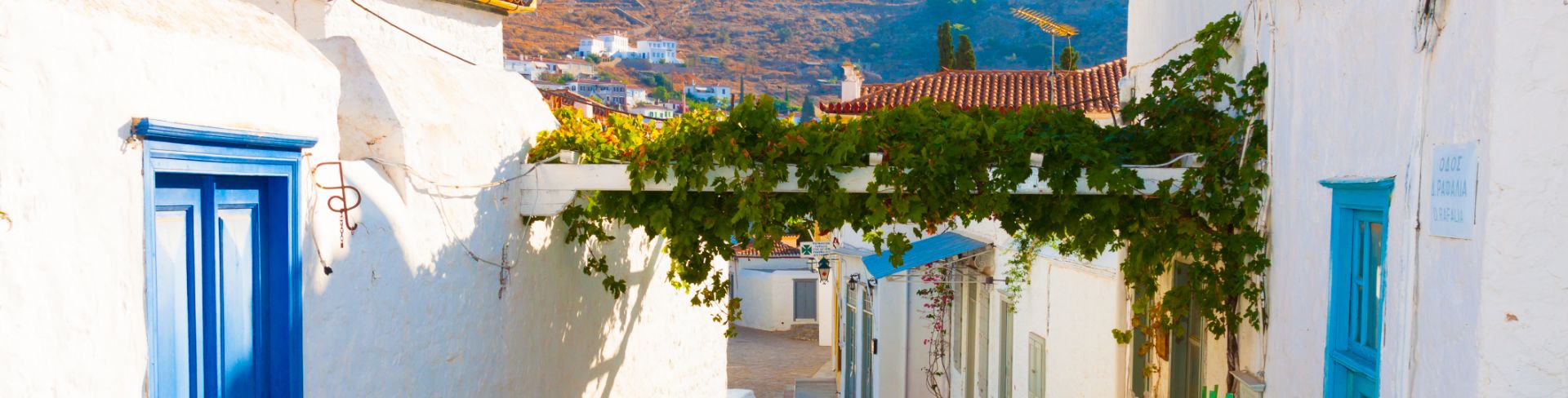 Bright blue doors dot white buildings lining an old stone street.