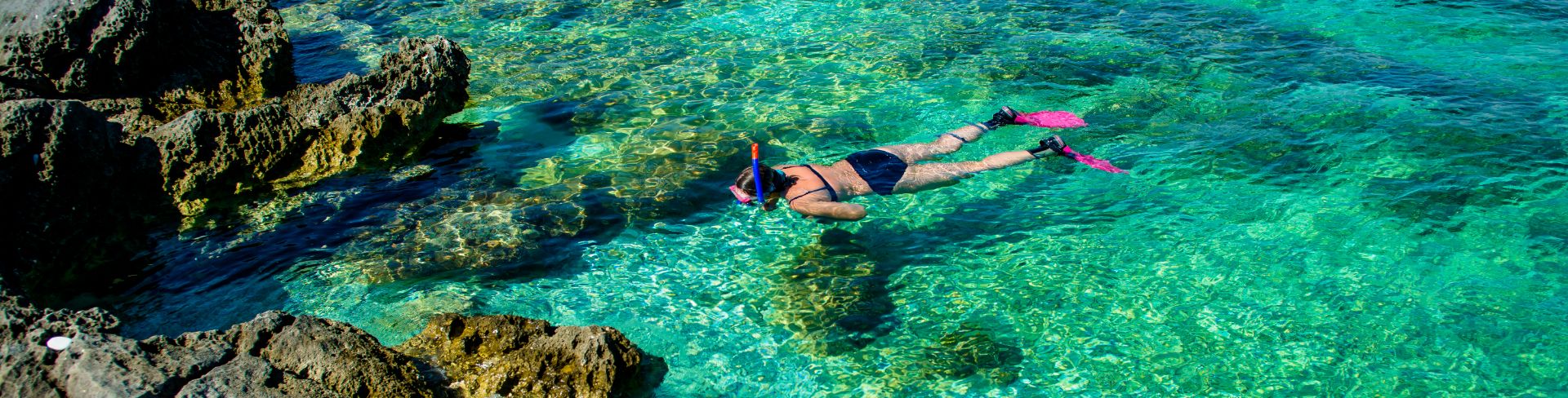 A person snorkels in crystal clear waters.