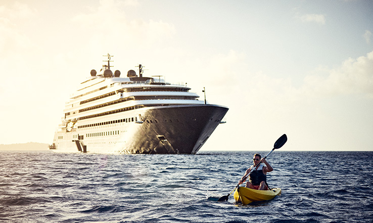 A person kayaks on ocean waters with Luminara in the background.