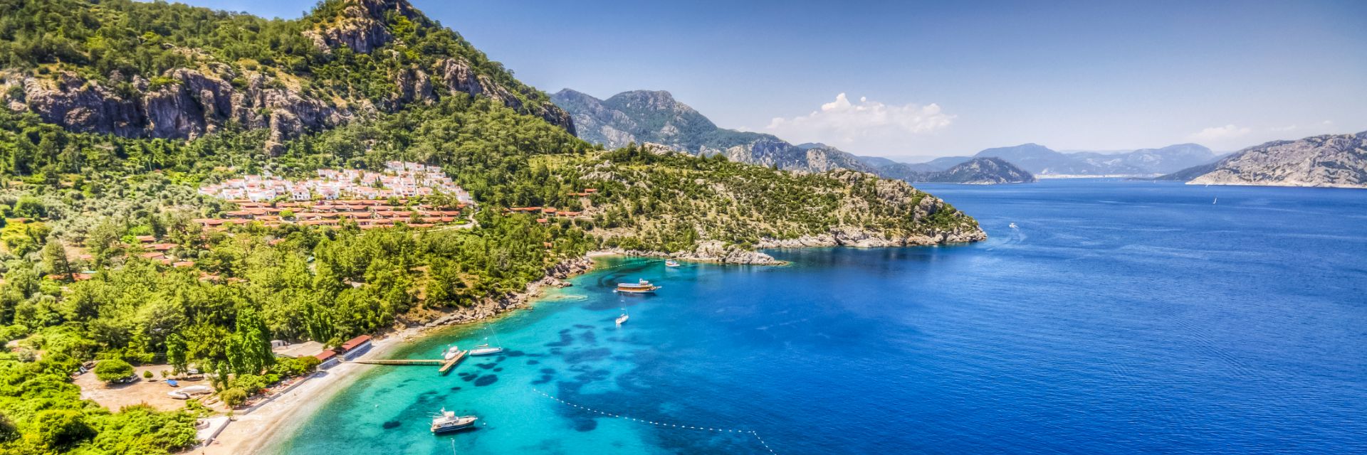 A mountainside bleeds into bright blue ocean waters in Marmaris, Turkey