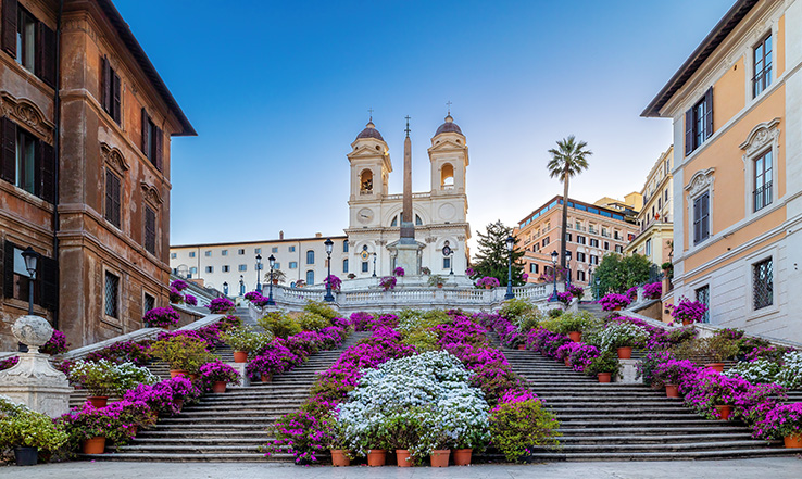 Flowers and stairs lead up to a tall building.