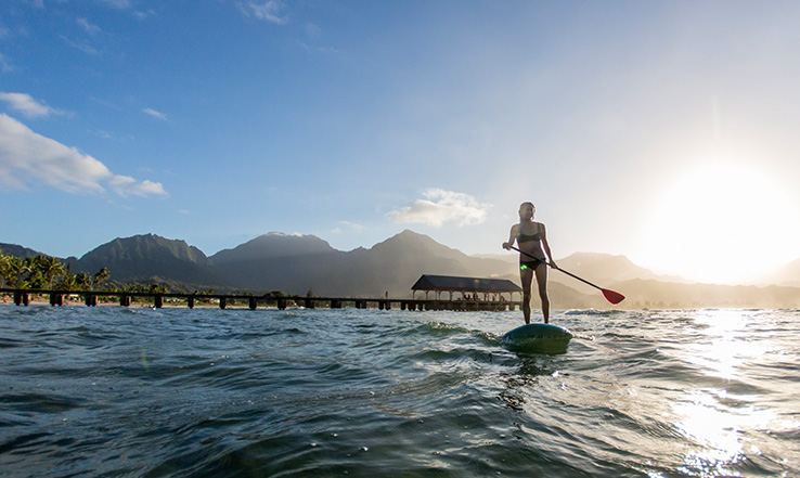 A person paddleboards on deep blue waters.