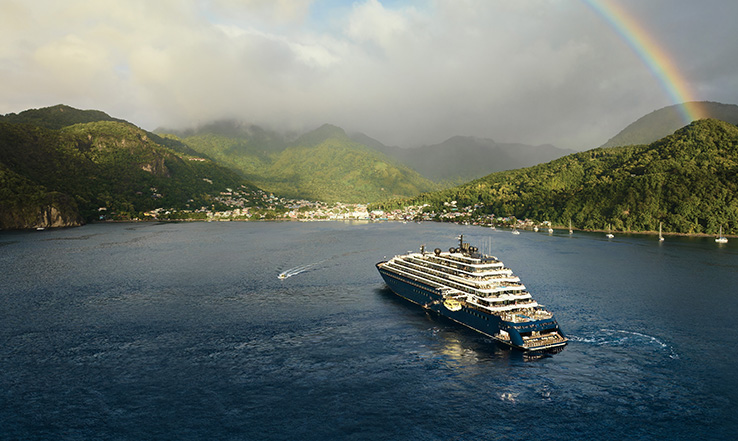 A rainbow appears out of bright green mountains, shining over Luminara.