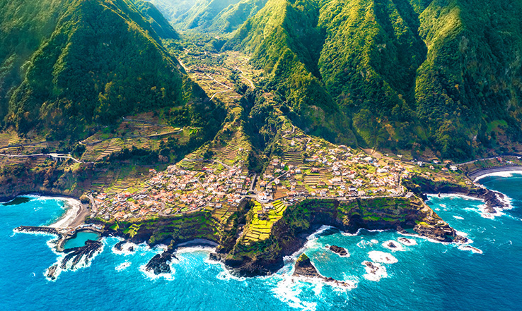Bright blue waters crash on the shore of a curvy coastline.