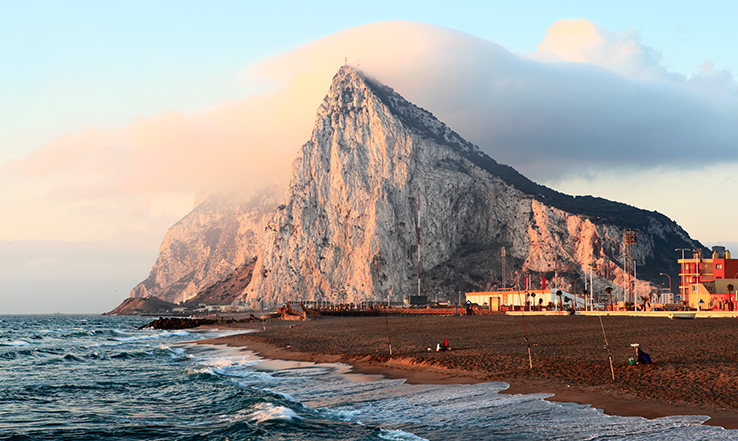 A large mountain looks out over deep blue ocean waters.