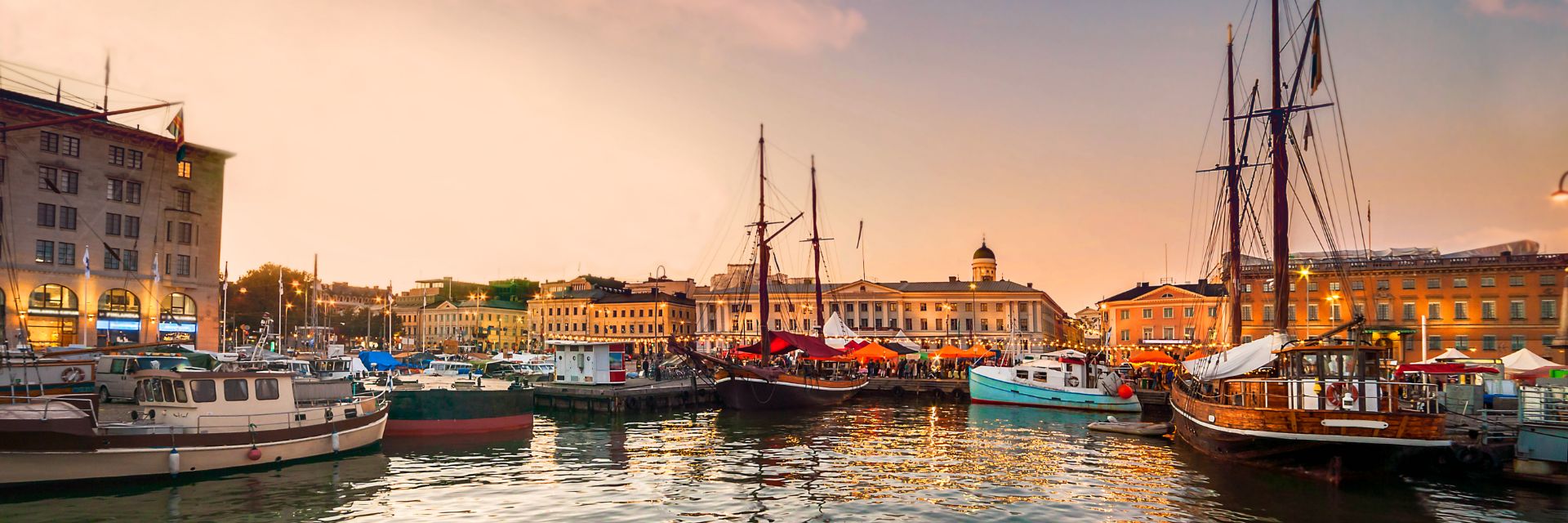 The sun sets over boats lining a waterway.