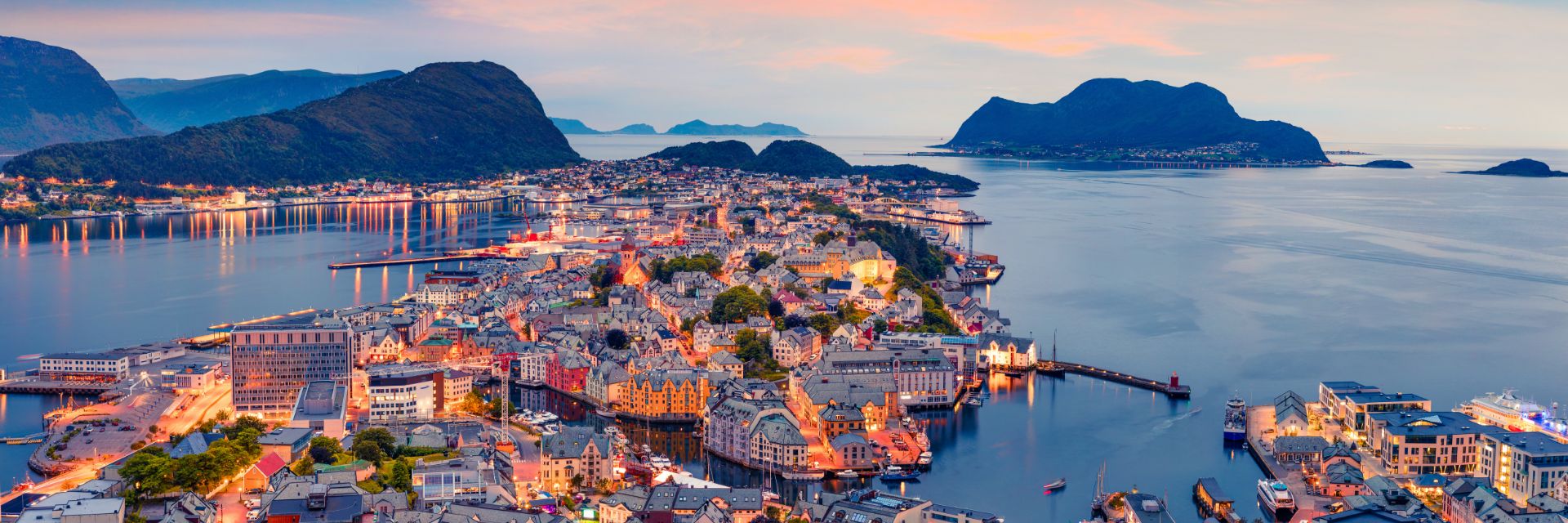 Lights illuminate stone buildings in a waterfront city.