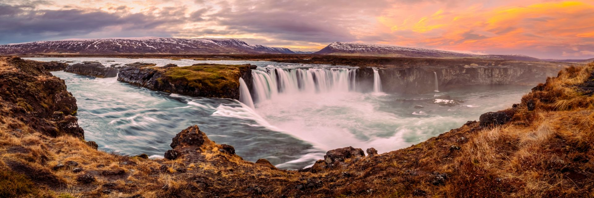 The sun sets on a large waterfall