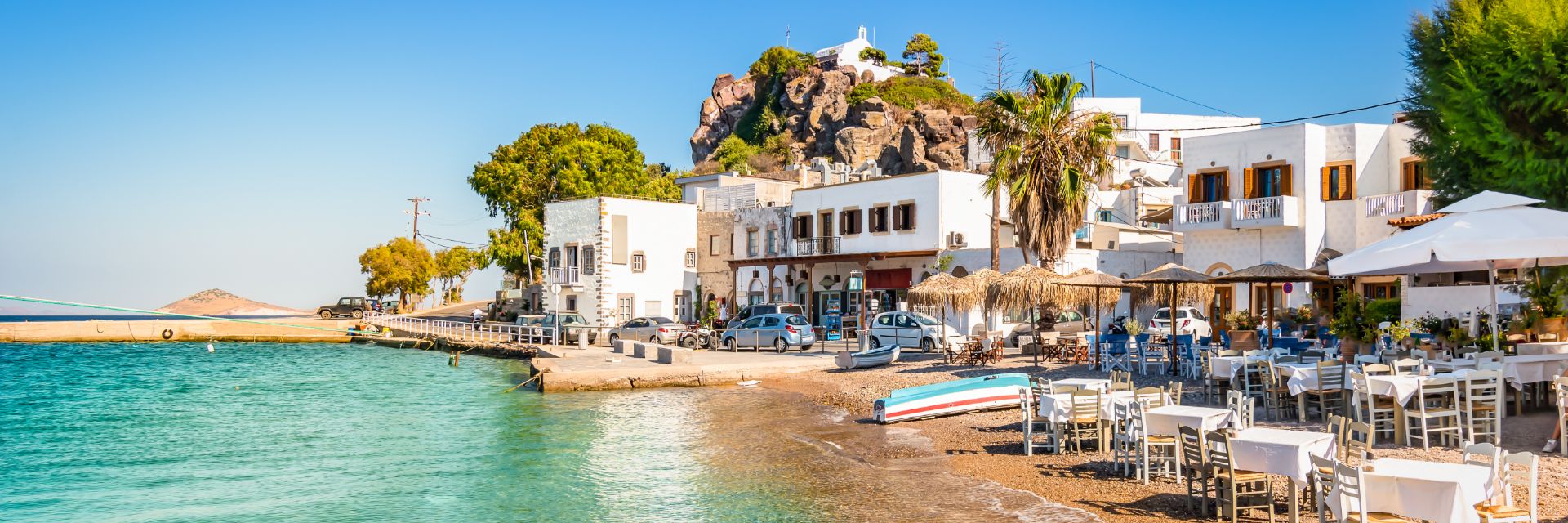 White buildings sit beachfront before a calm waterway.