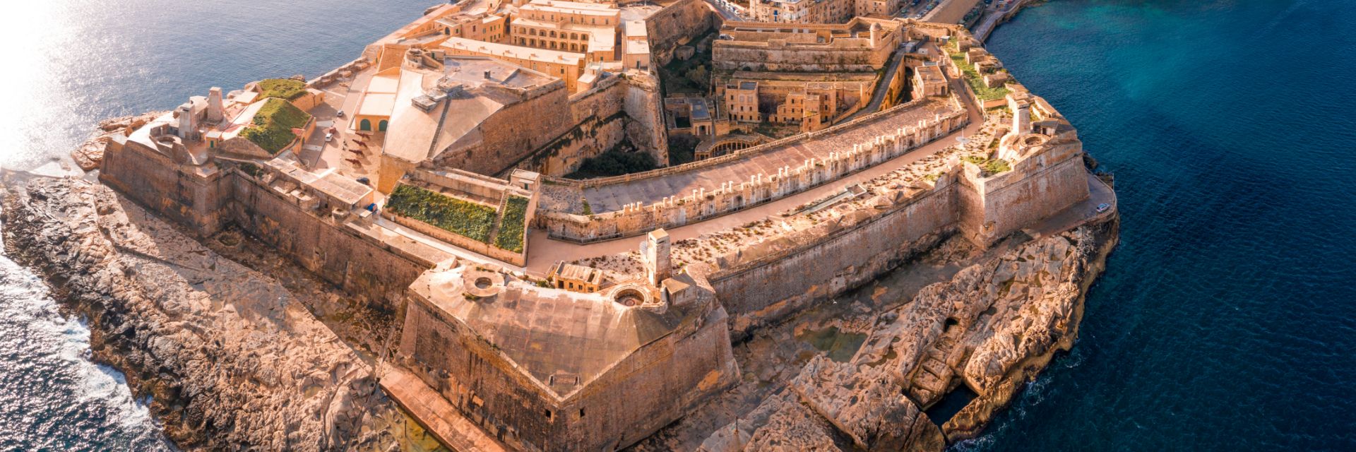 An old fort juts out into deep blue ocean waters. 