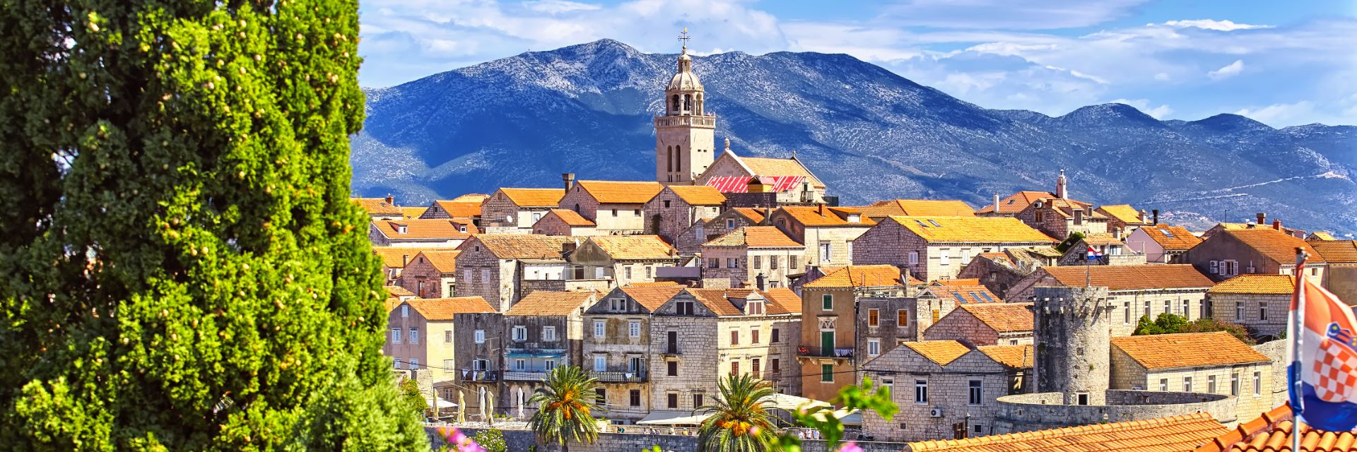 Terra Cotta Rooftops dot a town sitting before a mountain.