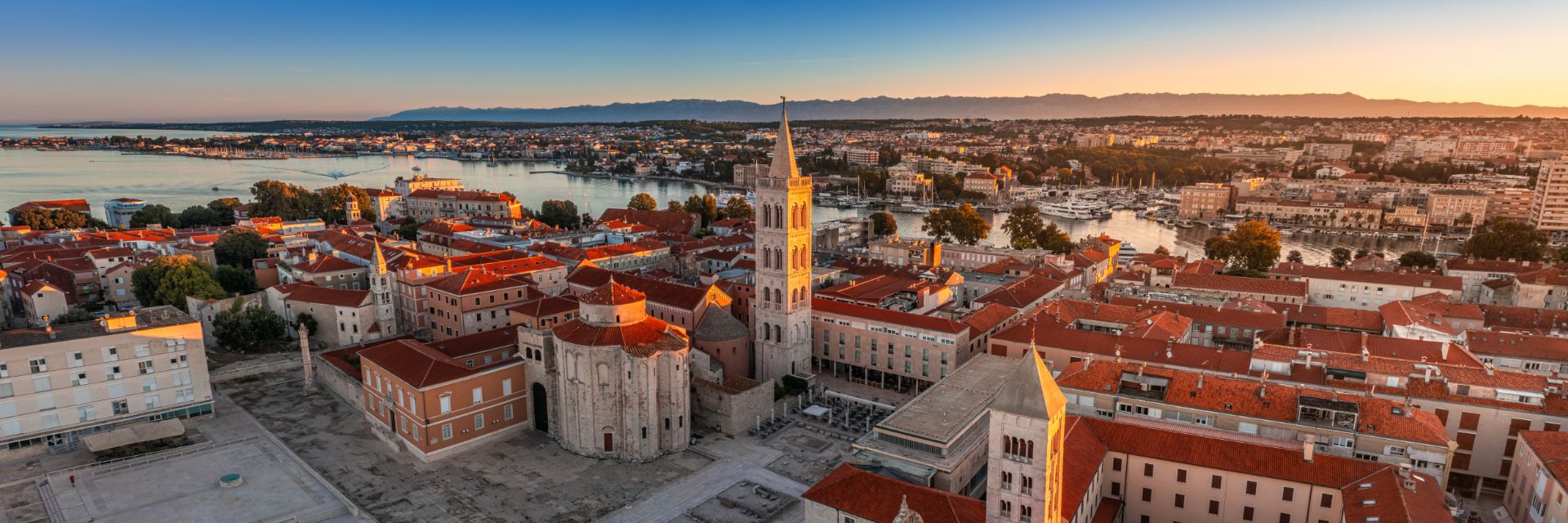 The sun illuminates buildings in a waterfront town.