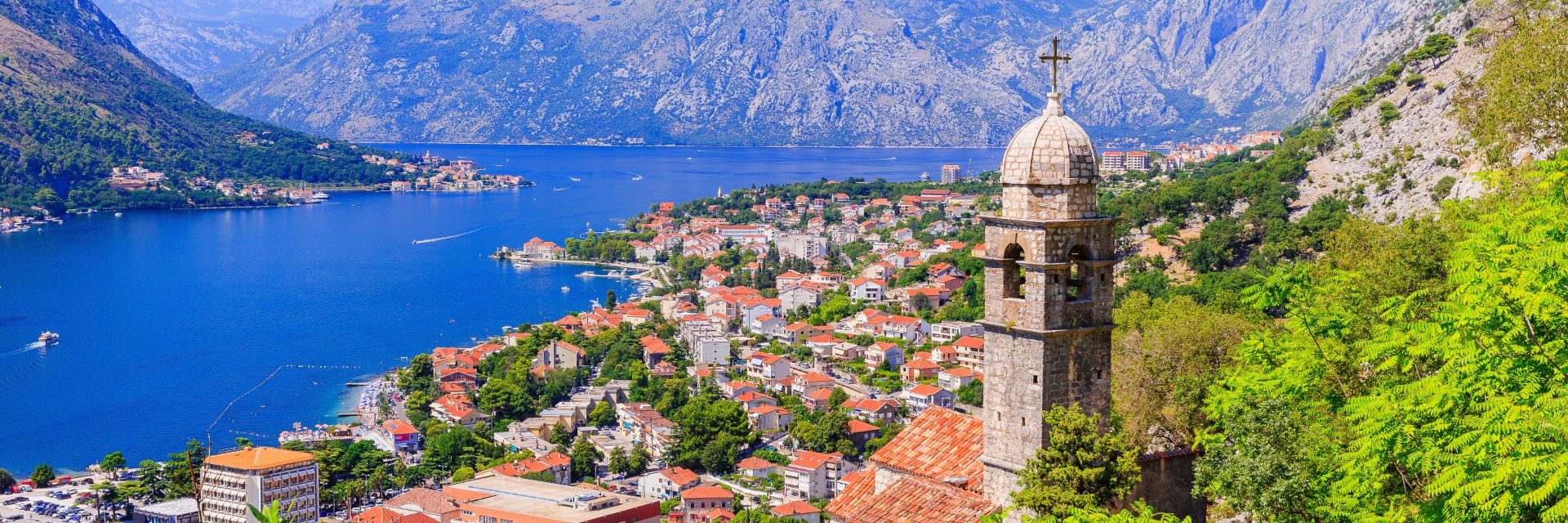 A deep blue waterway runs along a town sitting mountainside.
