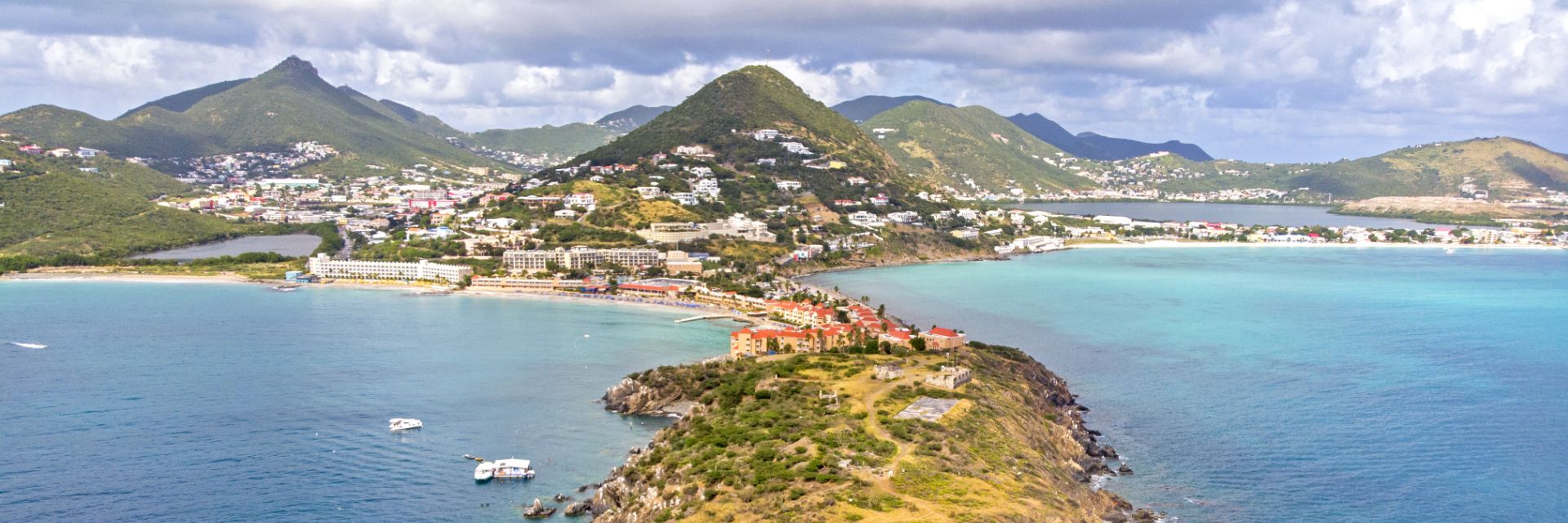 Mountains peeking out of ocean with small town in background