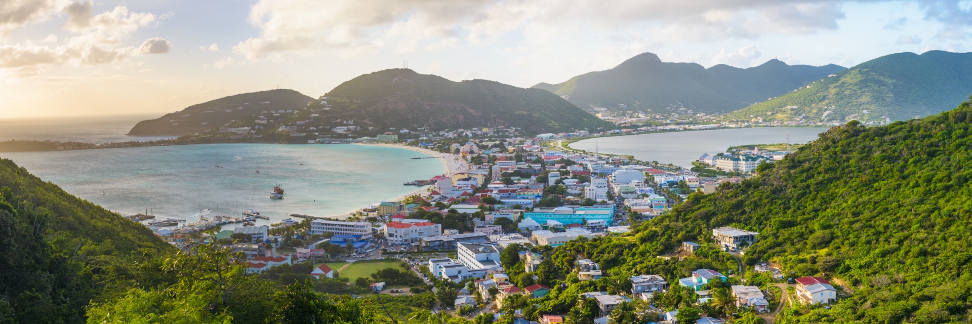 Homes fill the valley between two mountains covered in green foliage.