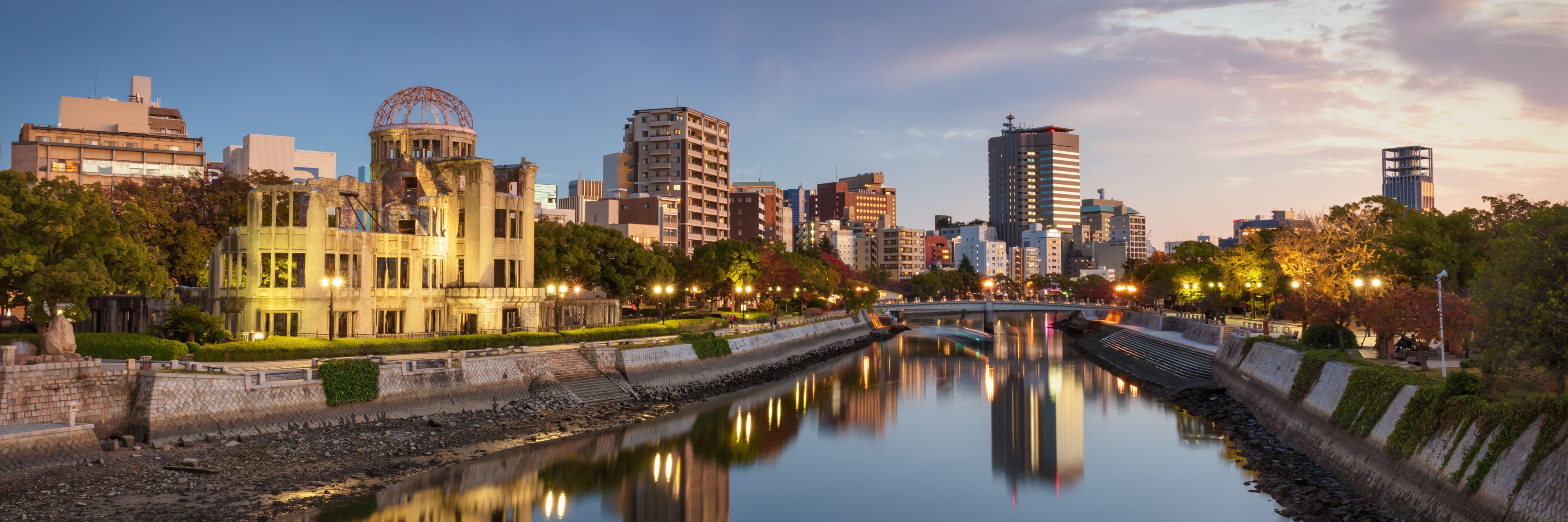 A waterway glitters at sunset reflecting the lights from local buildings.