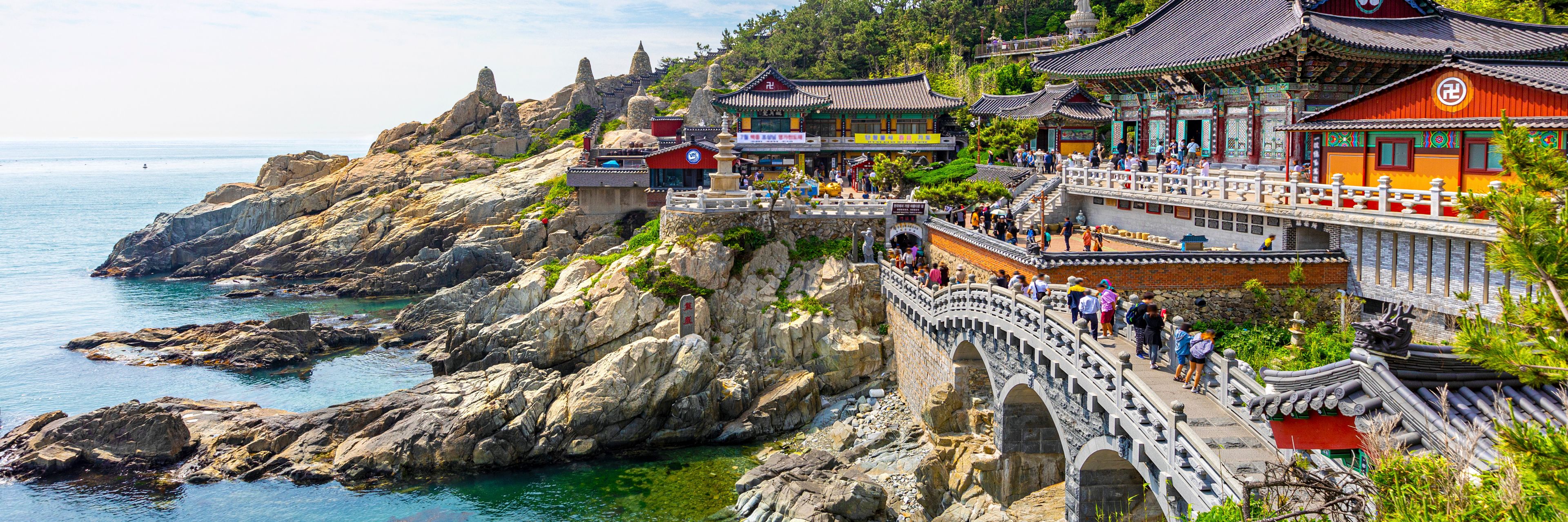 A waterway meets a rocky coastline spotted with bright, traditional buildings.