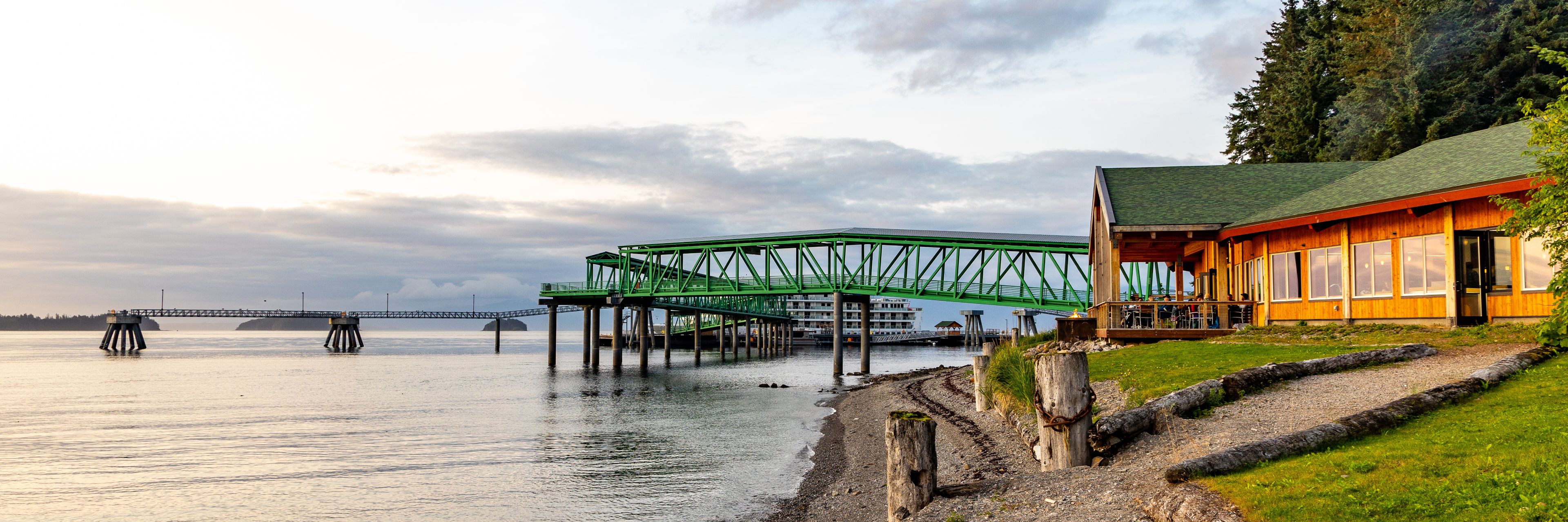A green bridge leads over the water from a building.