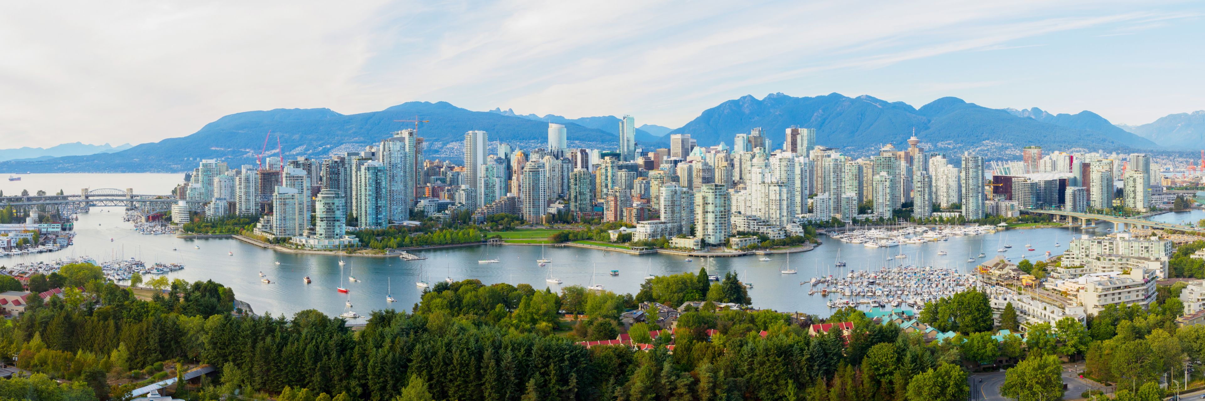 Buildings line a waterway back dropped by snow capped mountains.