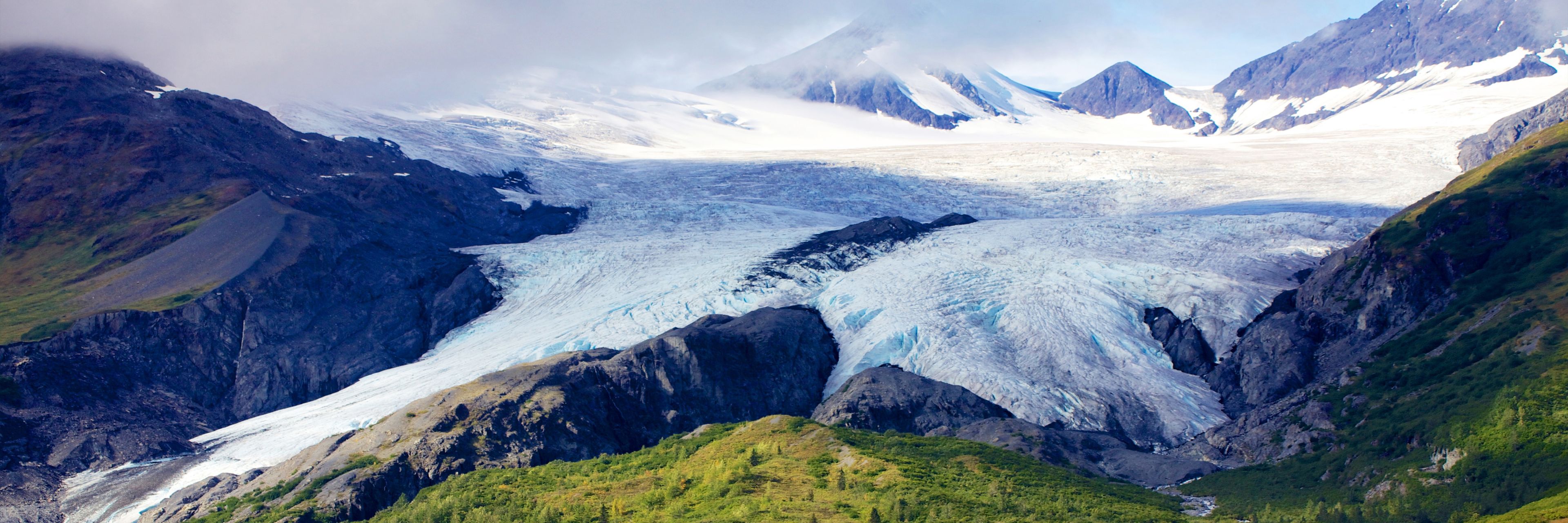 A glacier sits between several small mountains.