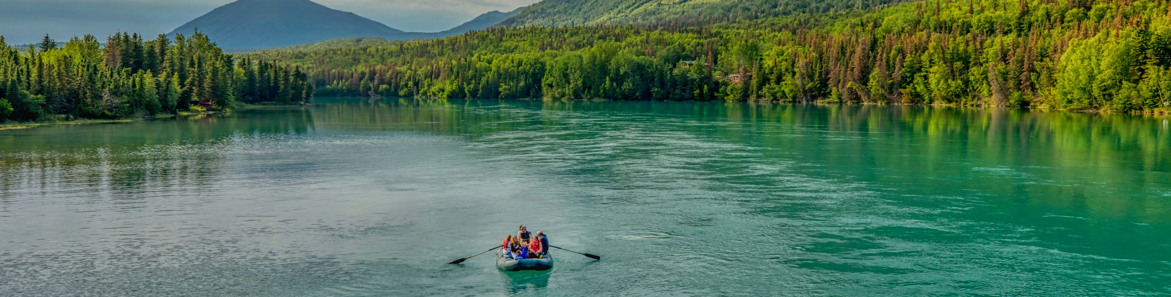 Green mountains sit behind a large still waterway.