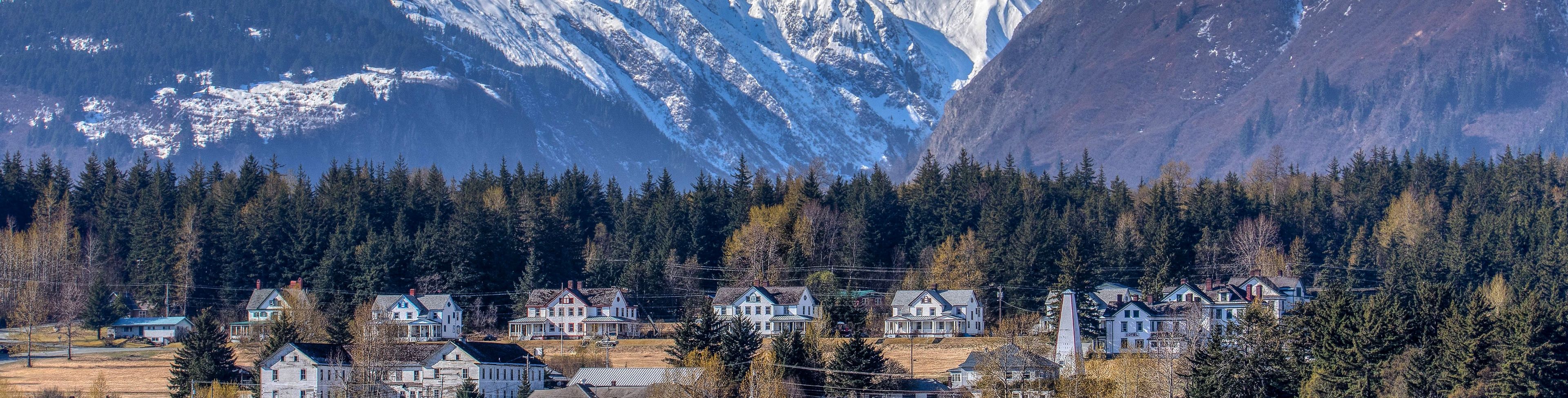 Snow capped mountains overlook a community of small homes.