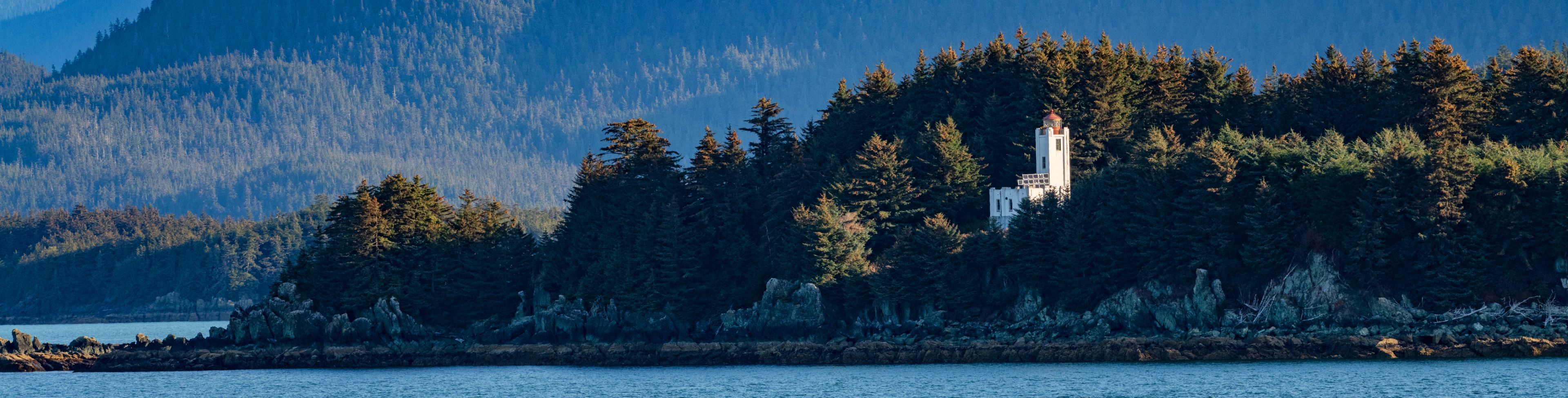Tree covered mountains backdrop a waterway.