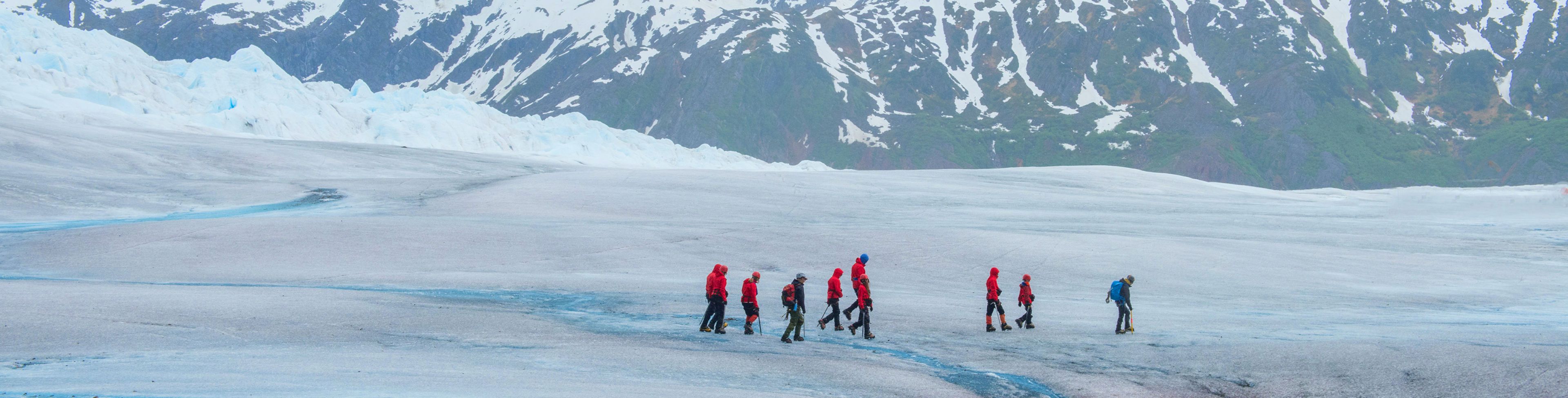 A group of people walk across an icy glacier.