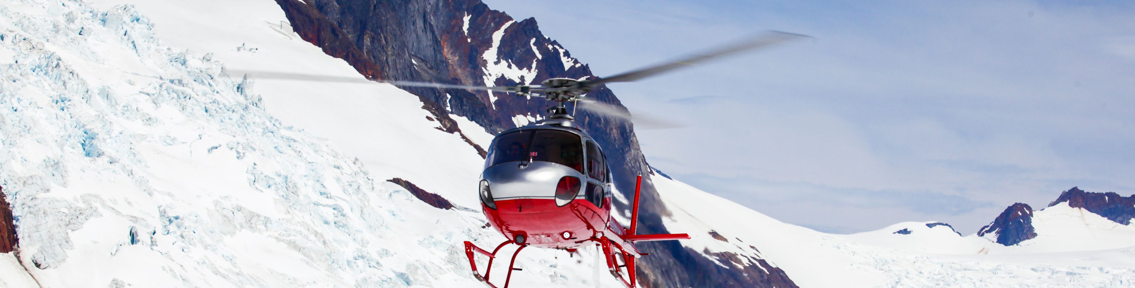 A helicopter hovers above a bright white snow sheet.