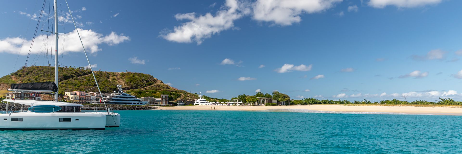A boat sits on bright blue waters near a sandy beach.
