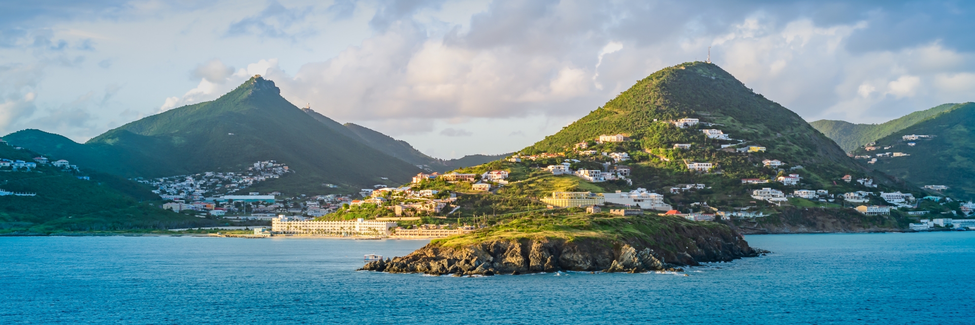 Bright blue waters surround an island covered in greenery.