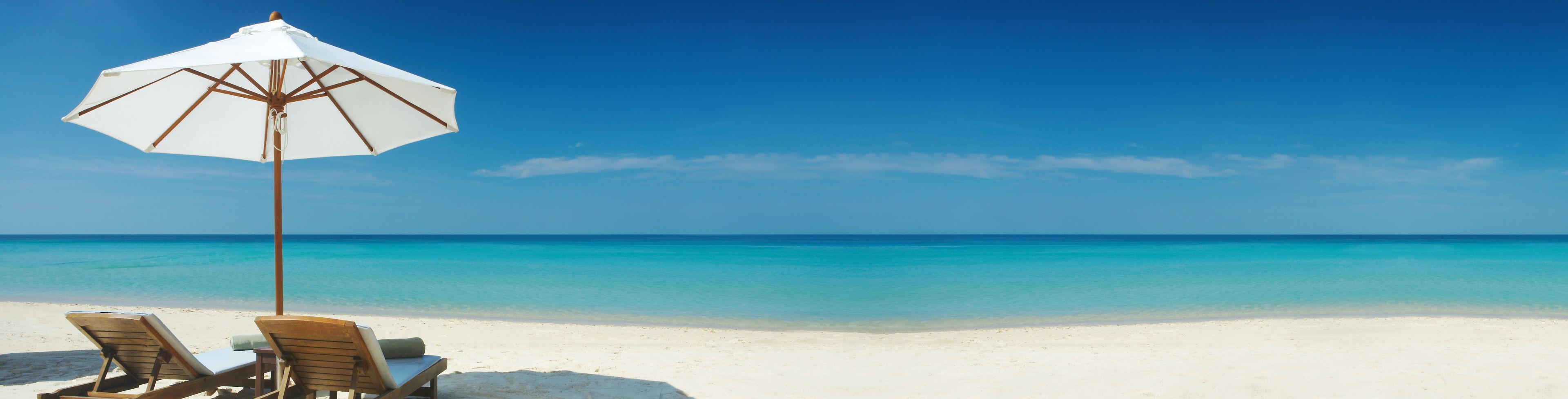 Two chairs under an umbrella on a sandy beach. 