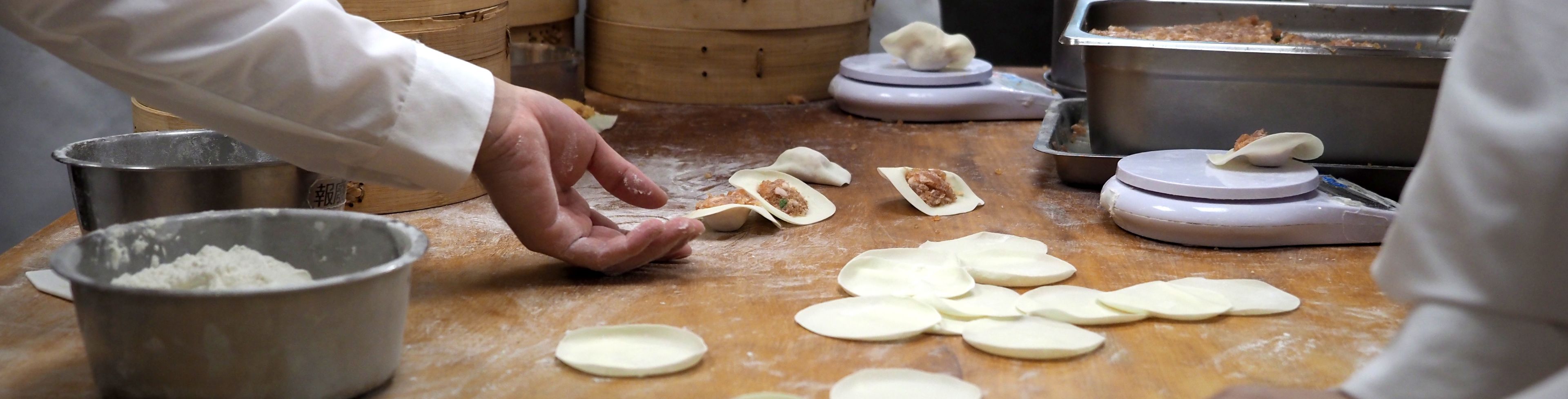 Chef's working on food on a cooking block in a kitchen. 