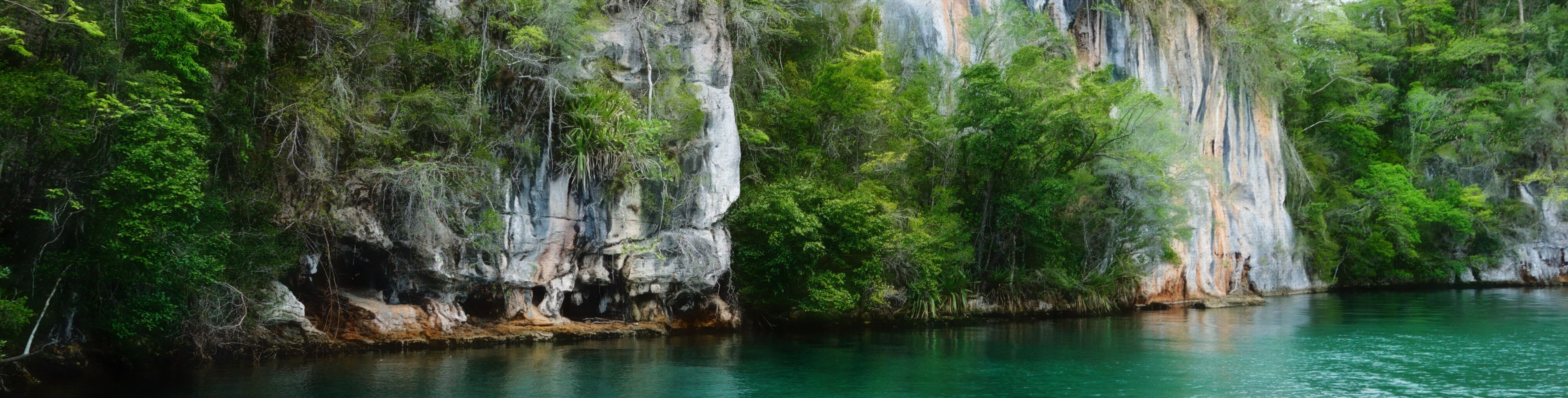 Clear blue/green water at the bottom of rocky cliff.