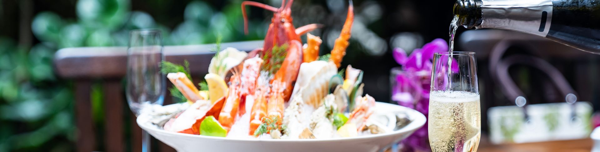 Bowl of lobster mixed with other ingredients on table with champagne. 