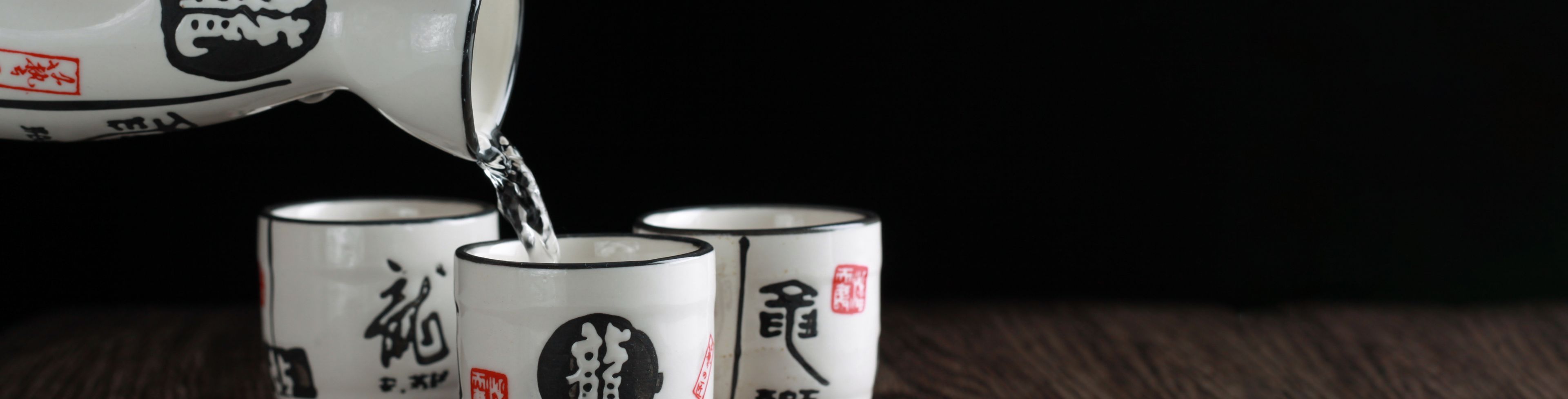 Liquid being poured into small cups from a pitcher. 