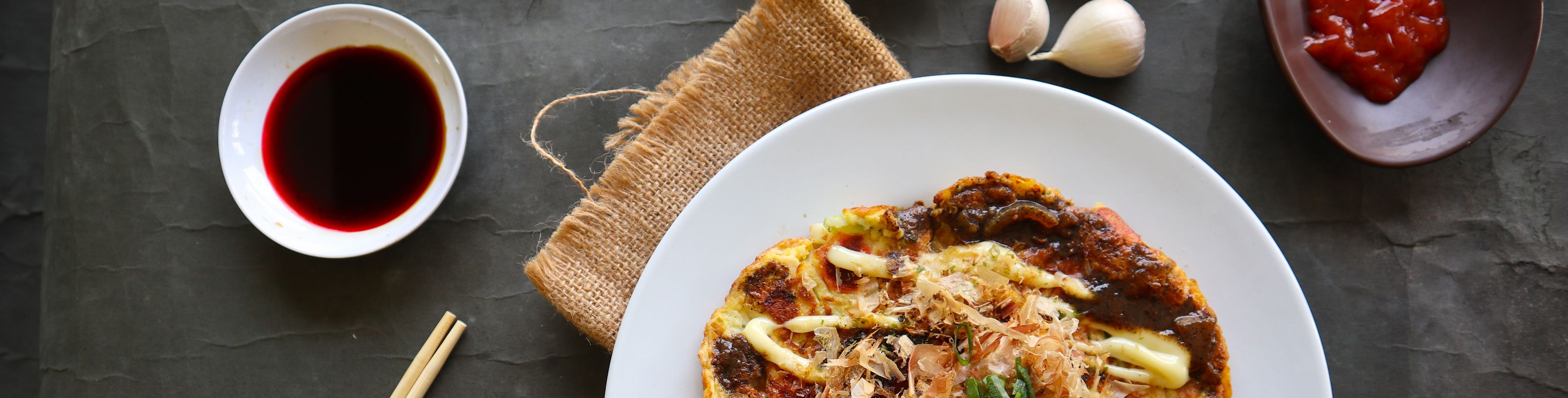 Round dishes full of different food and condiments on table. 