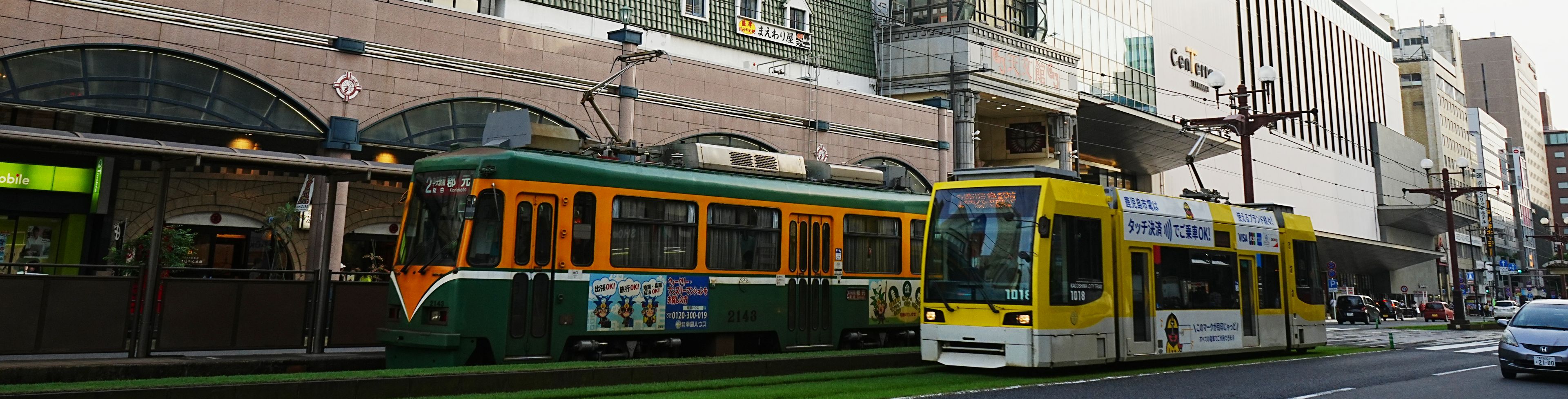 Street view of Kagoshima city buildings, with tram on street. 