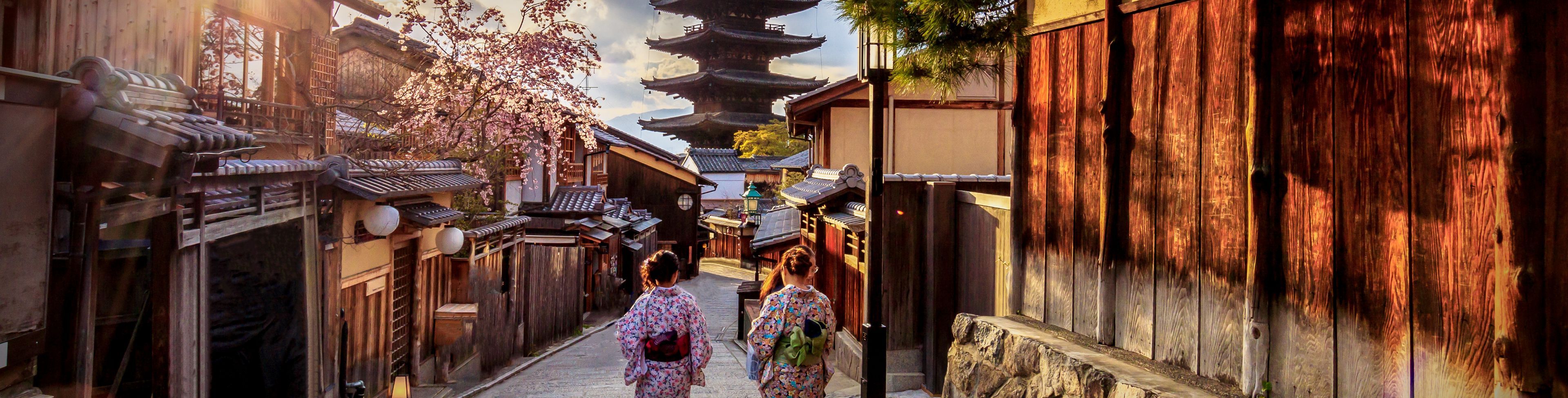 Two women dressed in Kimonos walking towards a temple. 