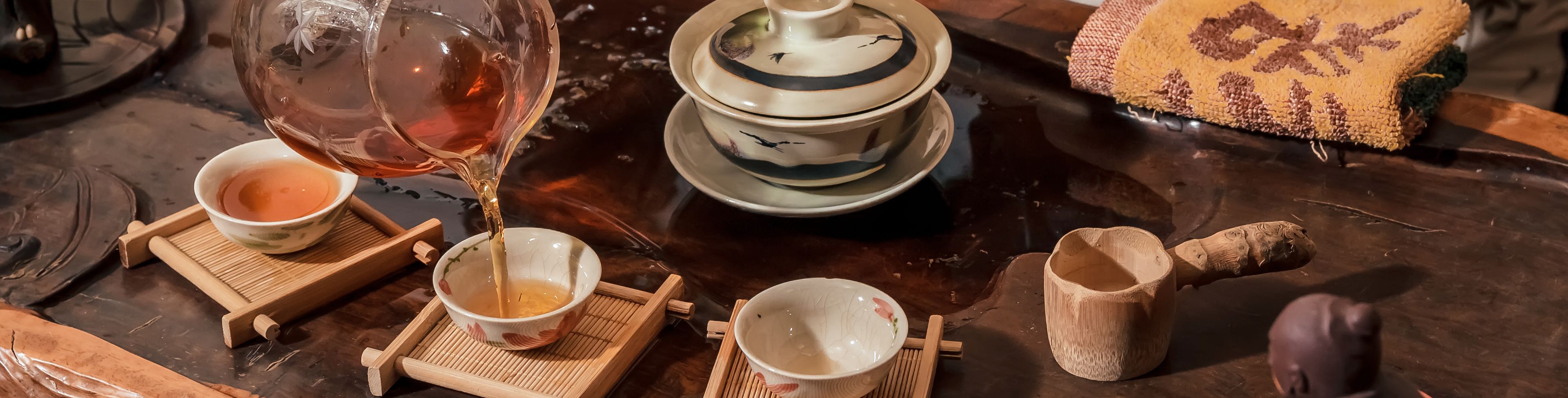 Woman pouring tea into small cups at a small table.