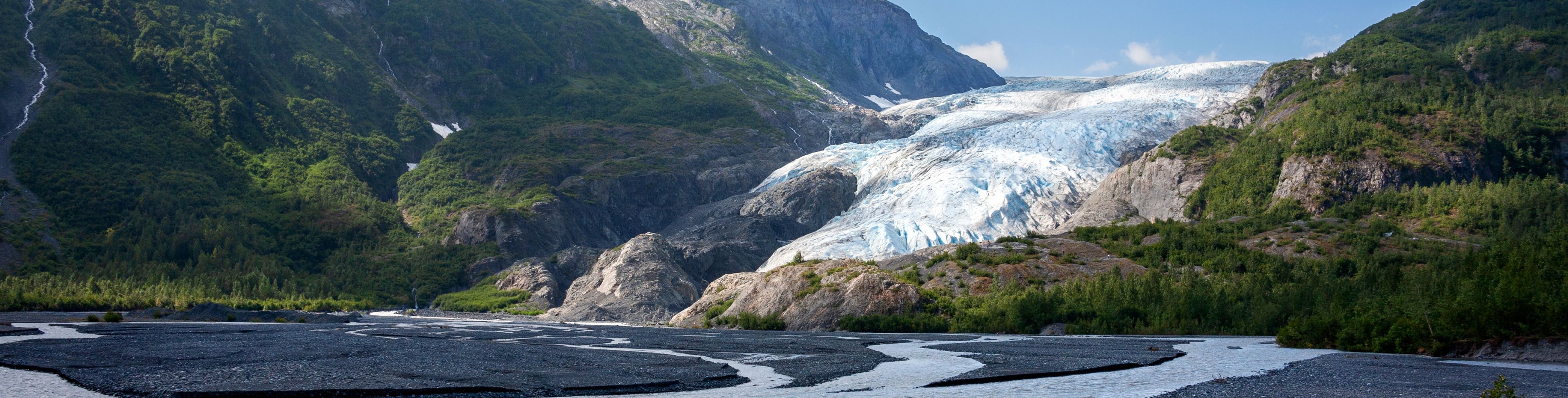 Glacier between two mountains, melting into water in a valley.