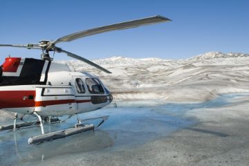 Helicopter parked on top of icy glacier. 