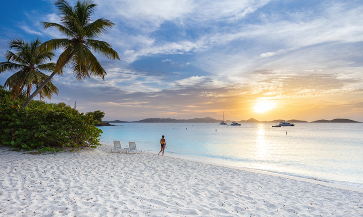 White sandy beach with the sun setting in the distance. 